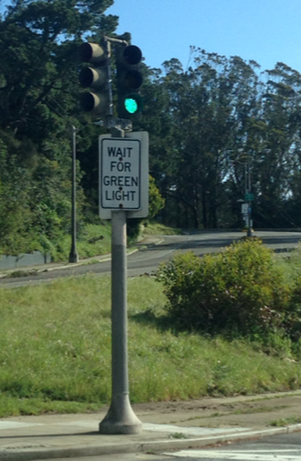 Green traffic light with "helpful" sign saying "WAIT FOR GREEN LIGHT"