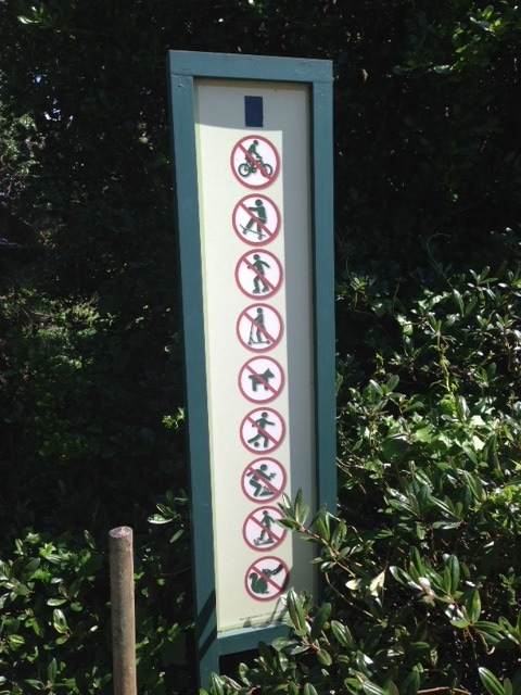 Sign listing huge list of rules, including:
"No biking"
"No skateboarding"
"No rollerblading"
"No scooters"
"No pets"
"No sports balls"
"No removal of leaves or rocks"
"No going off trail"
"No feeding wild animals"